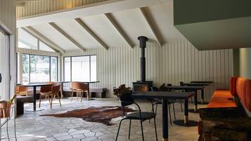 Un interior moderno con suelo de baldosas hexagonales, una chimenea central y una variedad de disposiciones de asientos, incluyendo un sofá y sillones.