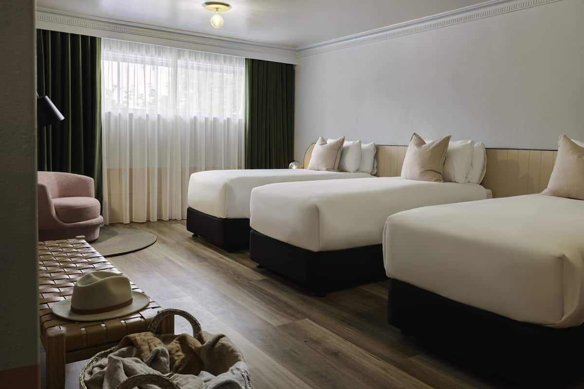 Een hotelkamer met twee bedden, een stoel, een hoed en een lamp.