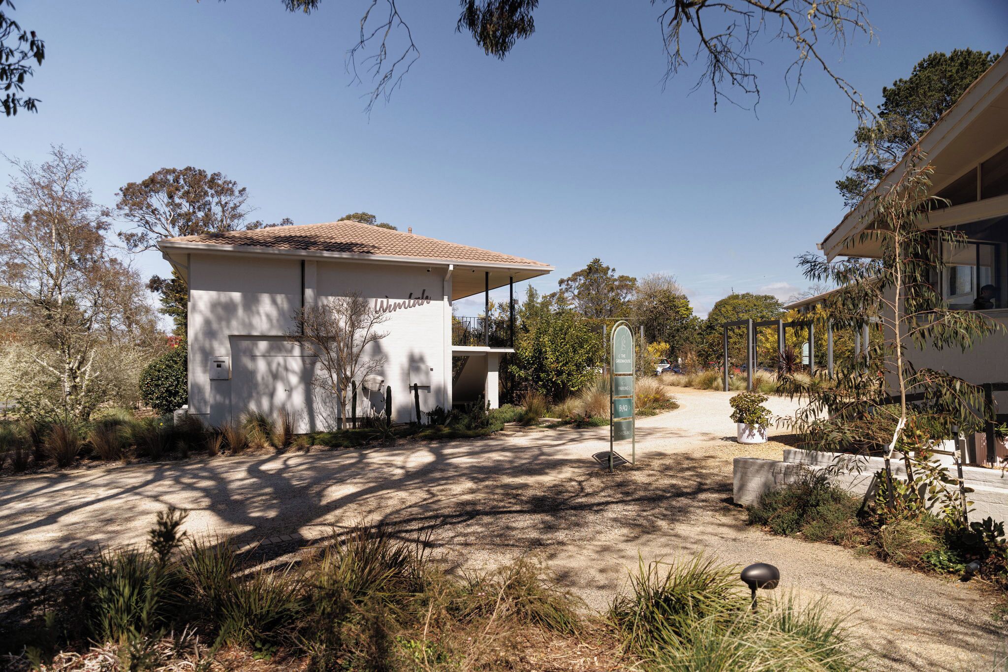 A modern building with a flat roof and a small balcony. There is a sign with a list of amenities.
