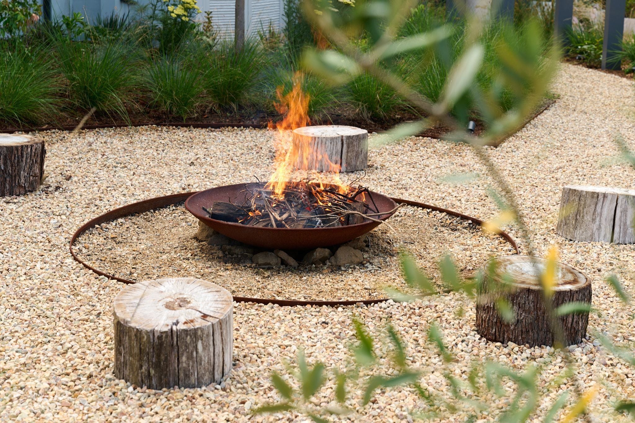 Un pozo de fuego rodeado de grava y tocones de madera.