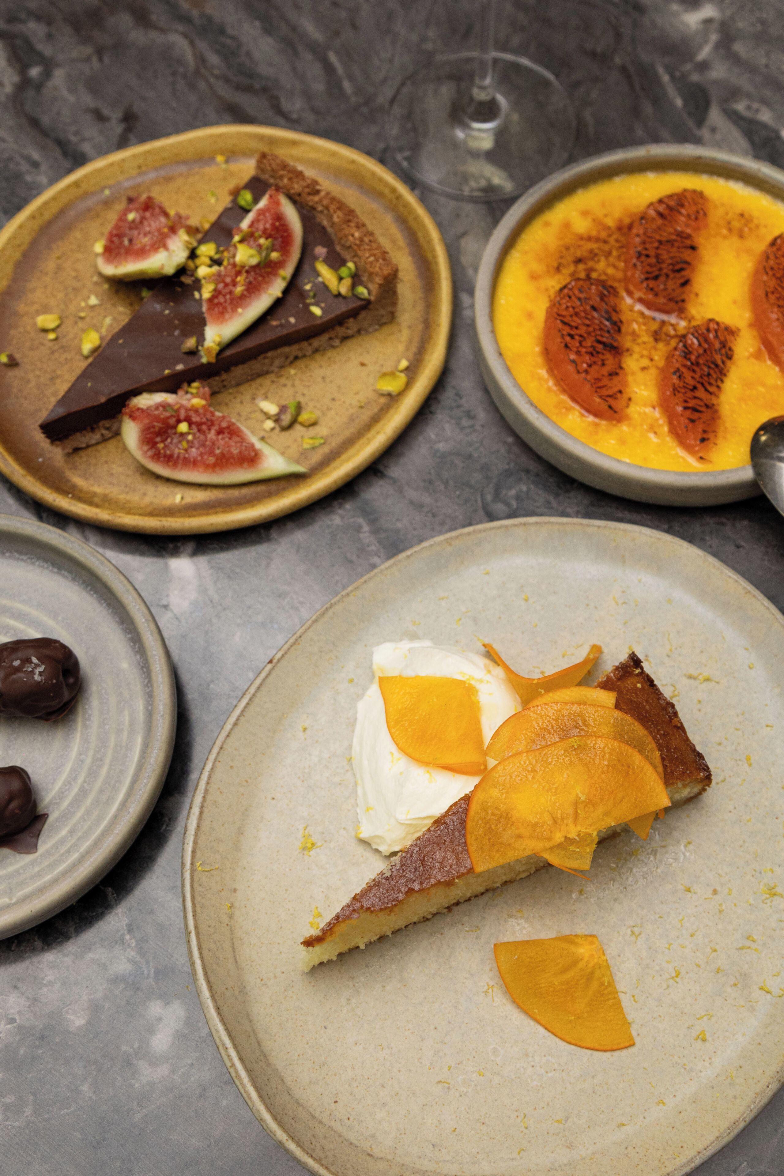 Une variété de desserts présentés sur des assiettes, notamment une part de tarte garnie de quartiers d’orange.