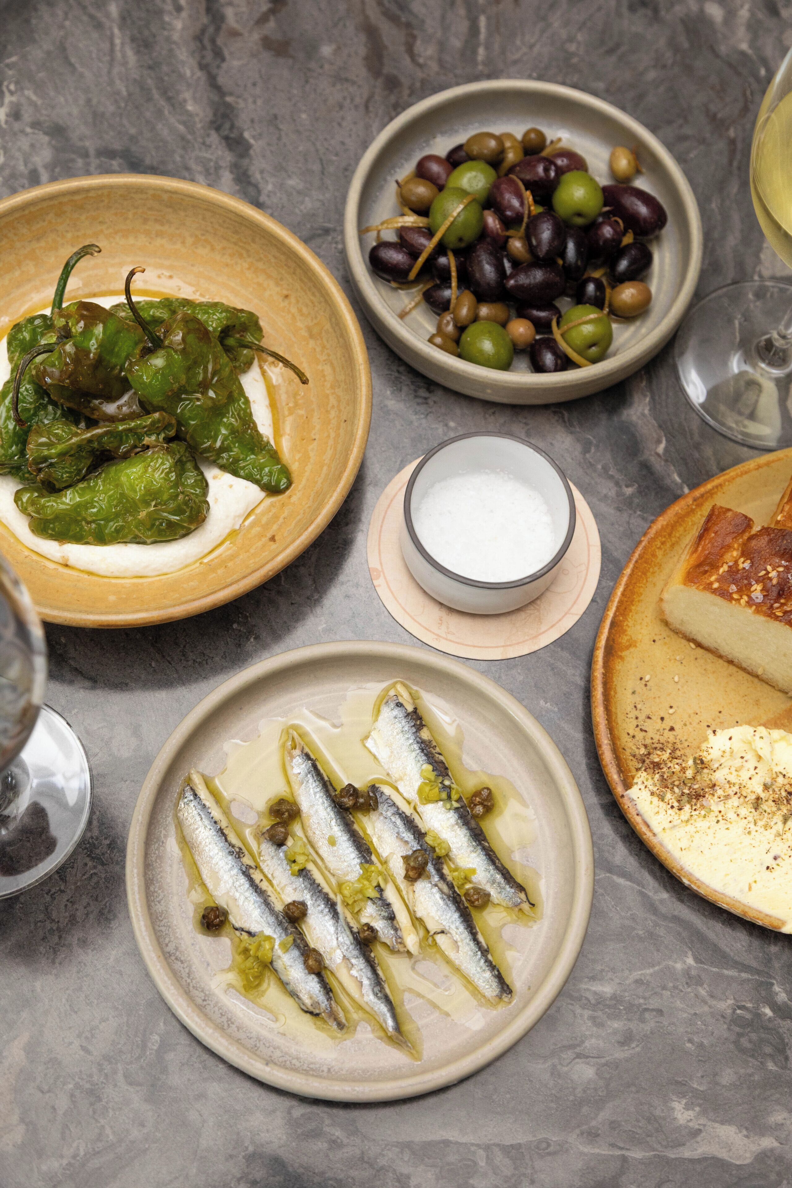 A table with various dishes including olives, fish, and a cheese plate.