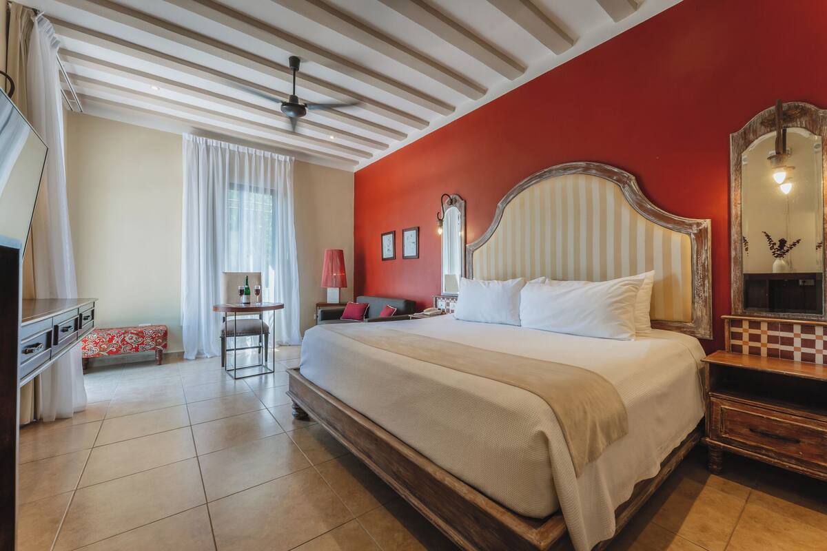 Een hotelkamer met een groot bed, een bureau, een stoel, een kledingkast en een spiegel.