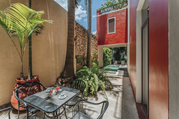 Une terrasse avec une table et des chaises, une plante en pot et un mur en pierre.
