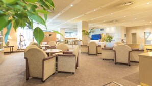 Un vestíbul d'hotel amb diverses zones d'estar, una recepció i un gran finestral.