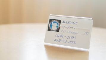 Tarjeta blanca con la palabra "MASSAGE" y caracteres japoneses, que indica un servicio de masaje.