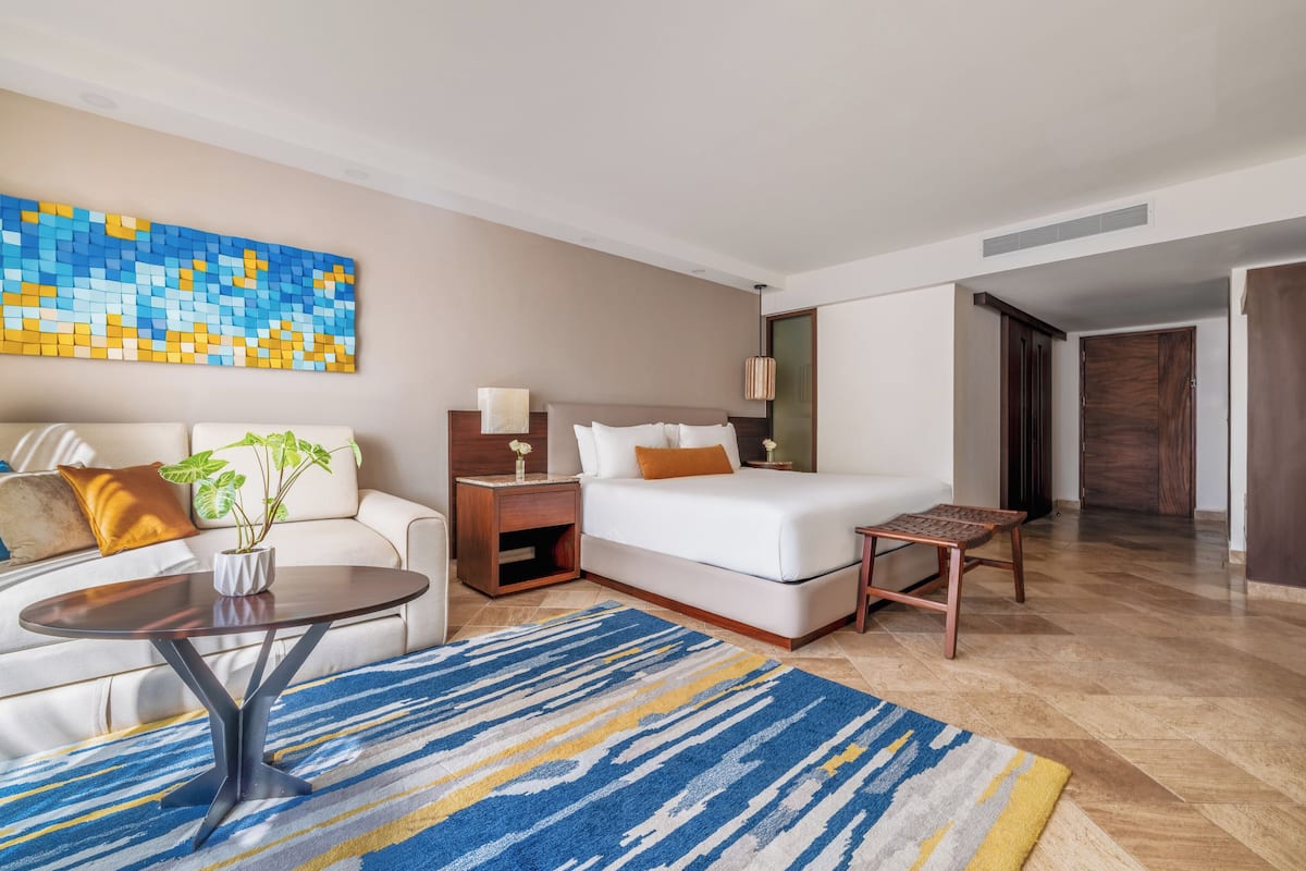 Una habitación de hotel con cama, sofá, una mesita y un tapete decorativo.