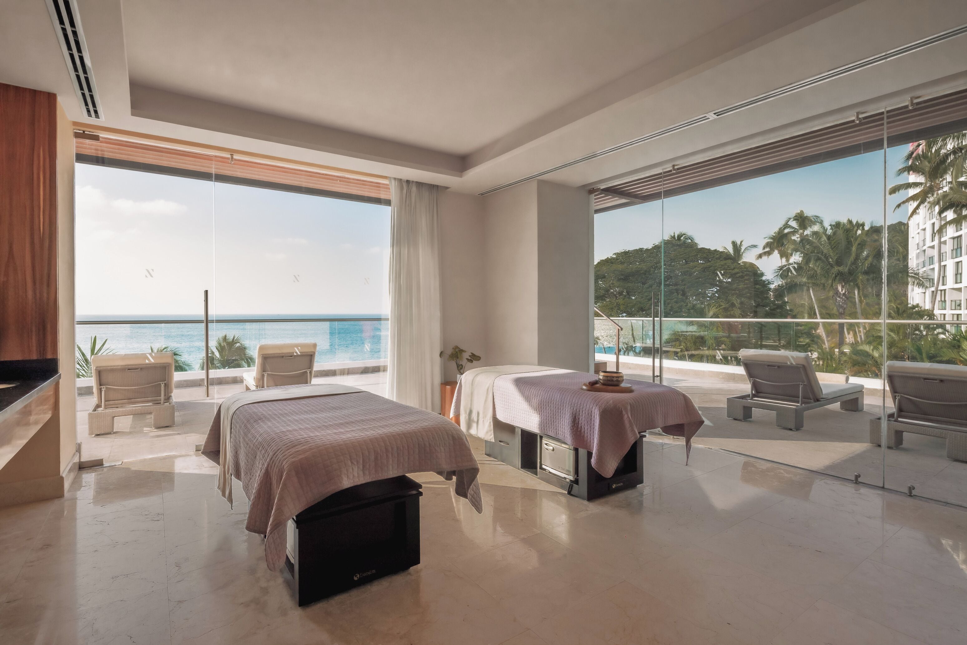 A modern hotel room with a large balcony, two beds, a TV, and a view of the ocean.