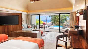 Habitación de hotel con una cama grande, escritorio, silla, televisor y vistas a una piscina y palmeras.