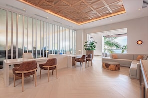 A modern hotel lobby with a reception desk, seating area, and a large window offering a city view.