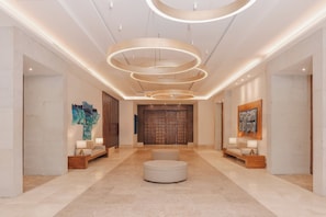 A spacious lobby with a central seating area, a modern chandelier, and artwork on the walls.