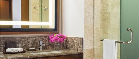 A modern bathroom with a marble sink, a large mirror, a glass shower enclosure, and a towel rack.