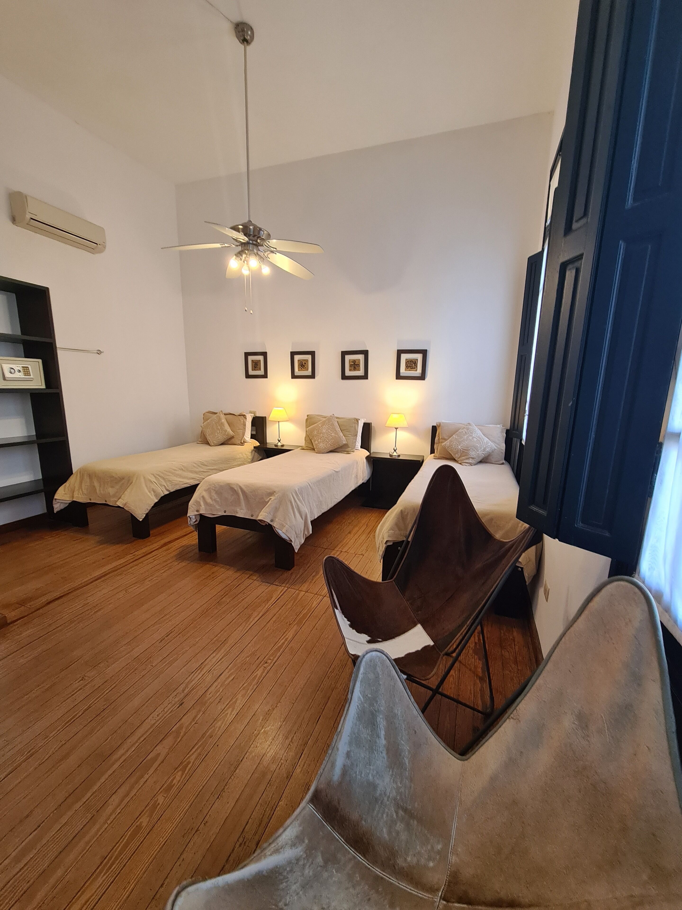 A bedroom with two beds, a ceiling fan, and a chair.