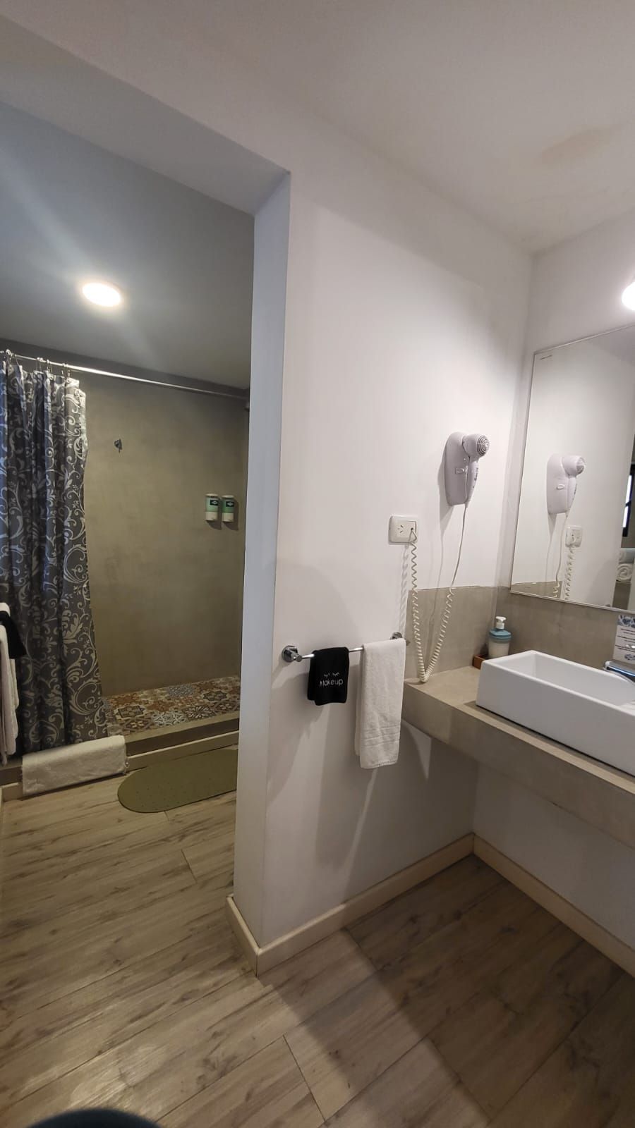 A bathroom with a shower, a sink, and a hairdryer mounted on the wall.