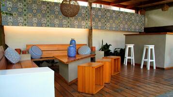 A wooden deck with a seating area, a bar, and a patterned wall.