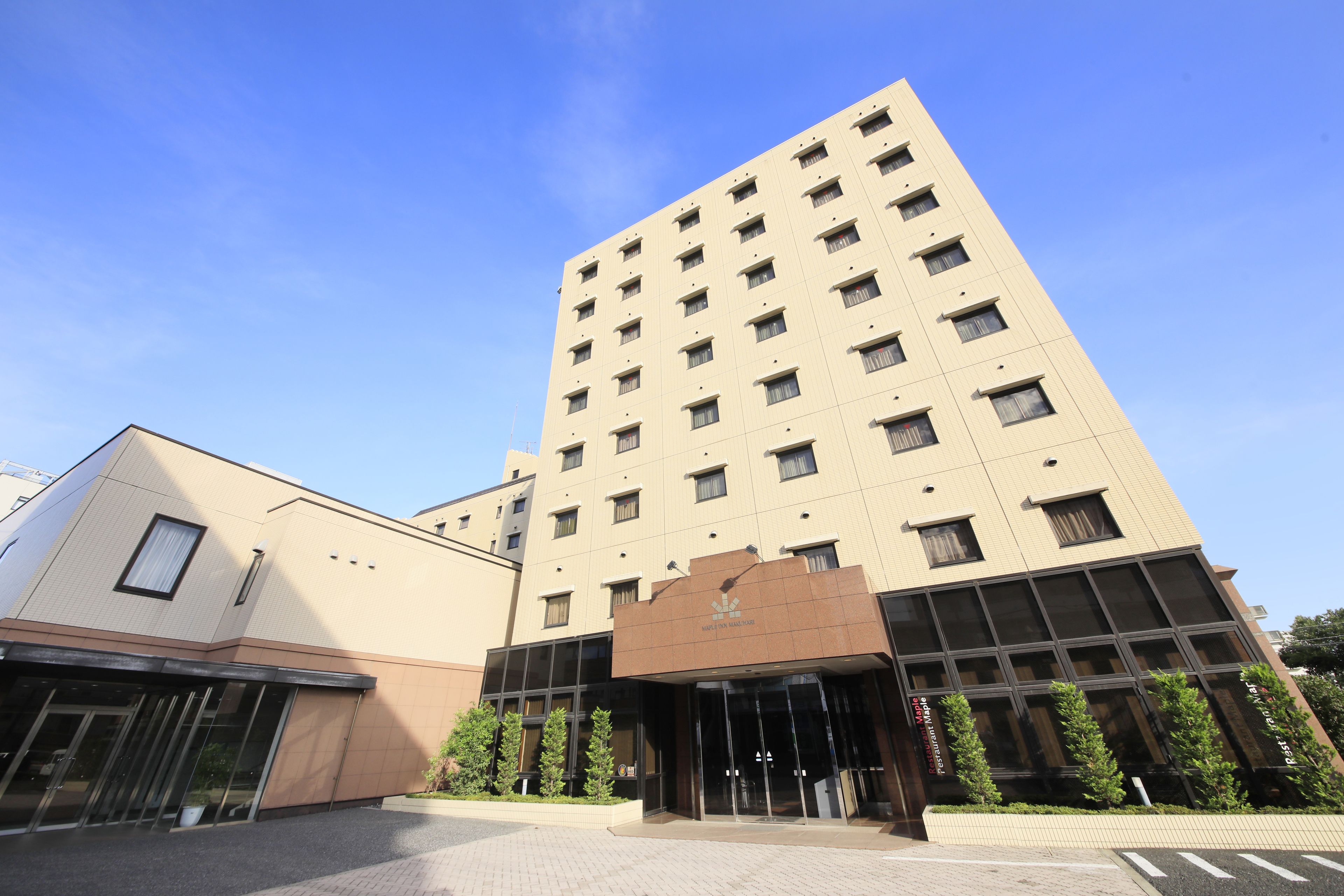 Een meerhoog hotel met een modern design, met een opvallende ingang met glazen deuren en een bord erboven.
