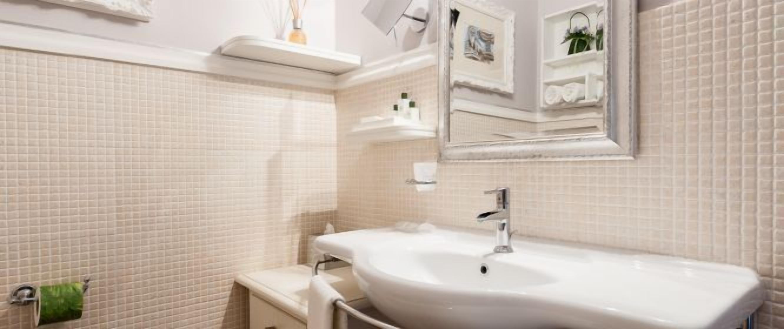 Une salle de bain avec un lavabo blanc, un miroir et des murs carrelés.