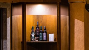 Un expositor de madera con botellas de vino, copas, un menú y un pequeño farol.