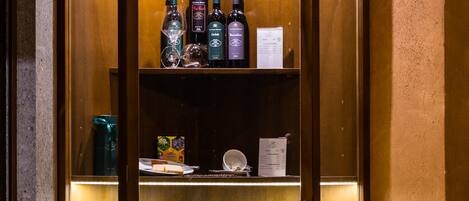 Un expositor de madera con botellas de vino, copas, un menú y un pequeño farol.