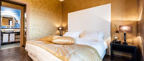 A hotel room with a large bed, bedside lamps, a nightstand, and a view of the bathroom.