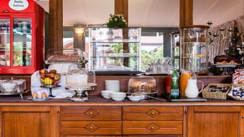 A breakfast buffet with various food items, a red milk cooler, and a coffee machine.
