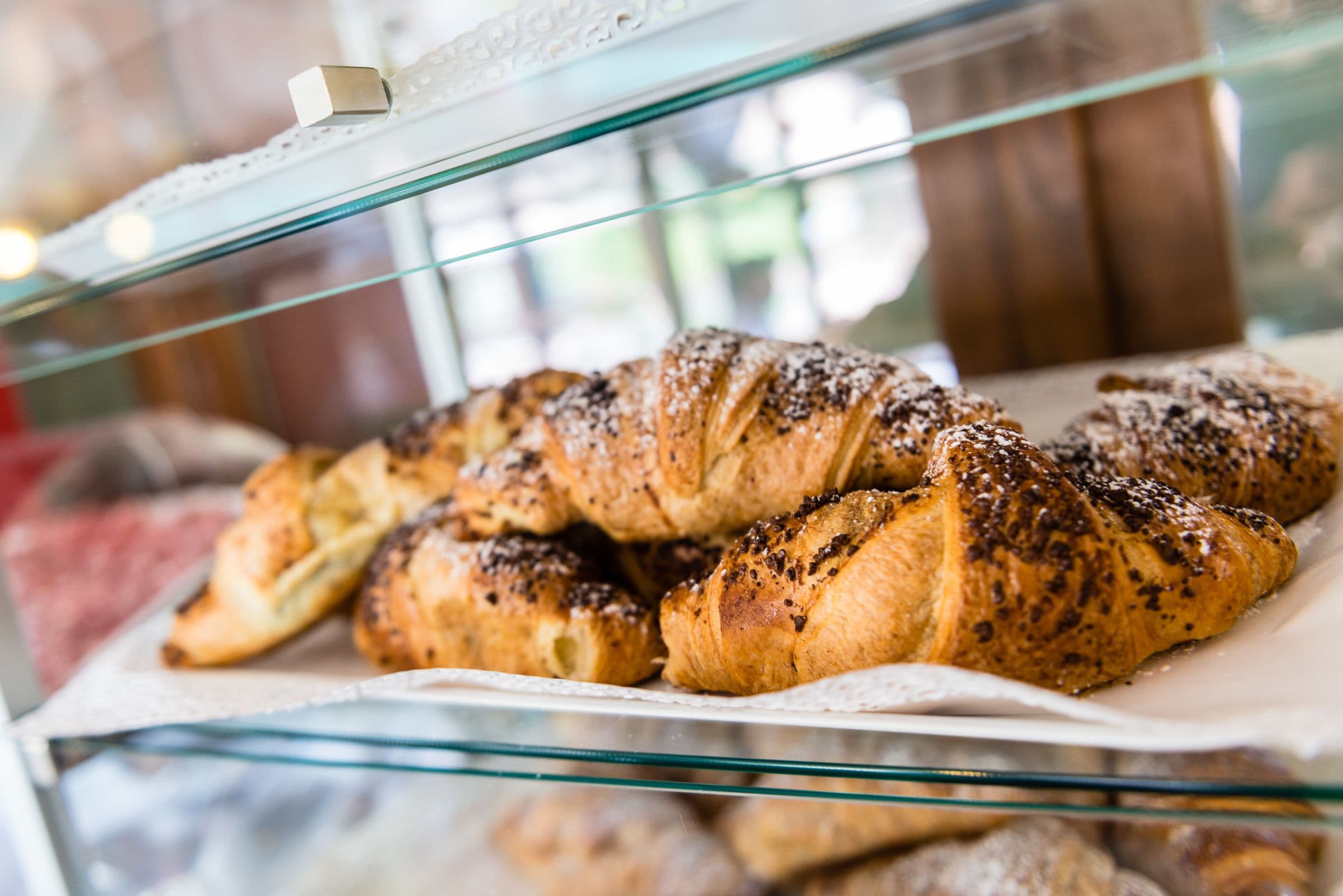 A display case with a variety of pastries, including croissants and other baked goods.