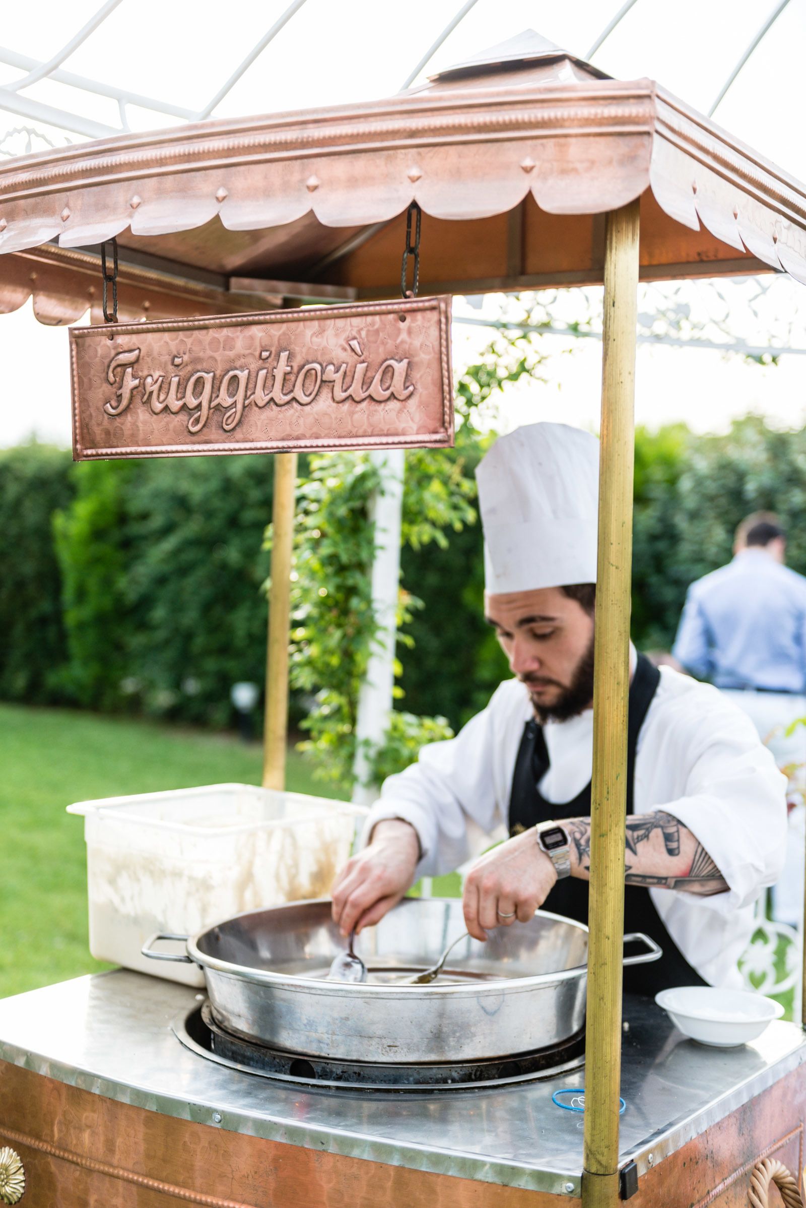 A chef preparing food at an outdoor food station named "Friggitorium."