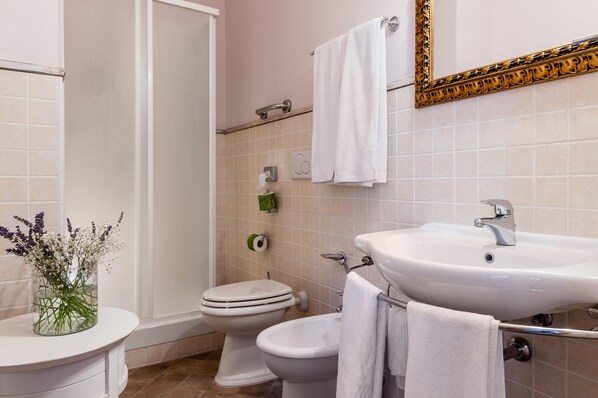 A bathroom with a toilet, bidet, sink, and a shower area. - Phi Hotel Corte delle Terme (Viterbo)