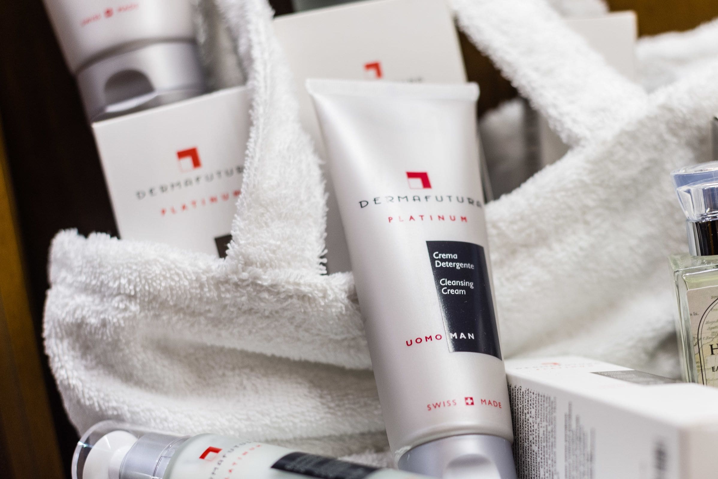 A display of DermaFuture Platinum products, including a cleansing cream and a serum, arranged on a white towel.
