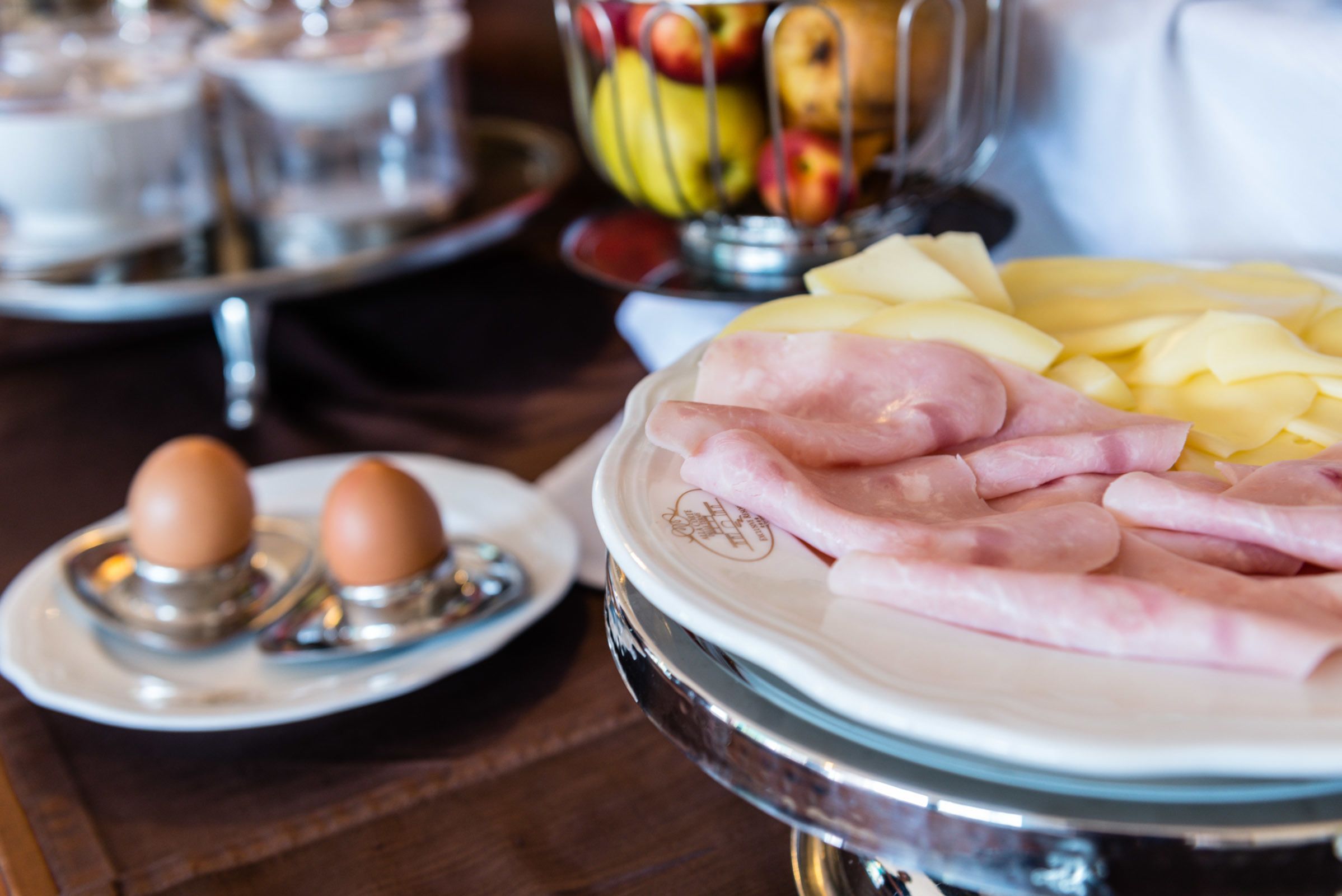 A breakfast buffet with ham, eggs, and fruit.