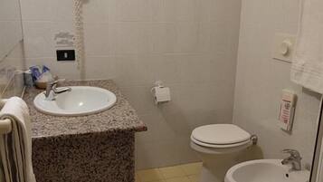 Un baño pequeño con lavamanos, inodoro, bidé y un perchero para toallas.