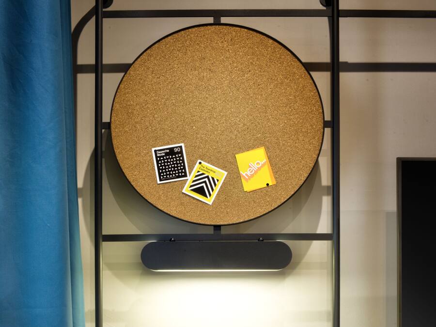 A modern workspace with a corkboard, a laptop, and a chair.