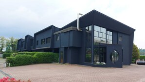 A modern two-story building with a dark facade, large windows, and a circular entrance. - Stay Hotel (Brunello)