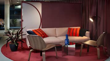 Una sala de estar moderna con un sofá, dos sillones, una mesa de centro y una planta en maceta.