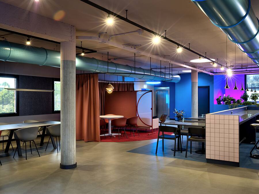 A modern conference room with a long table, chairs, and a bar area with stools.
