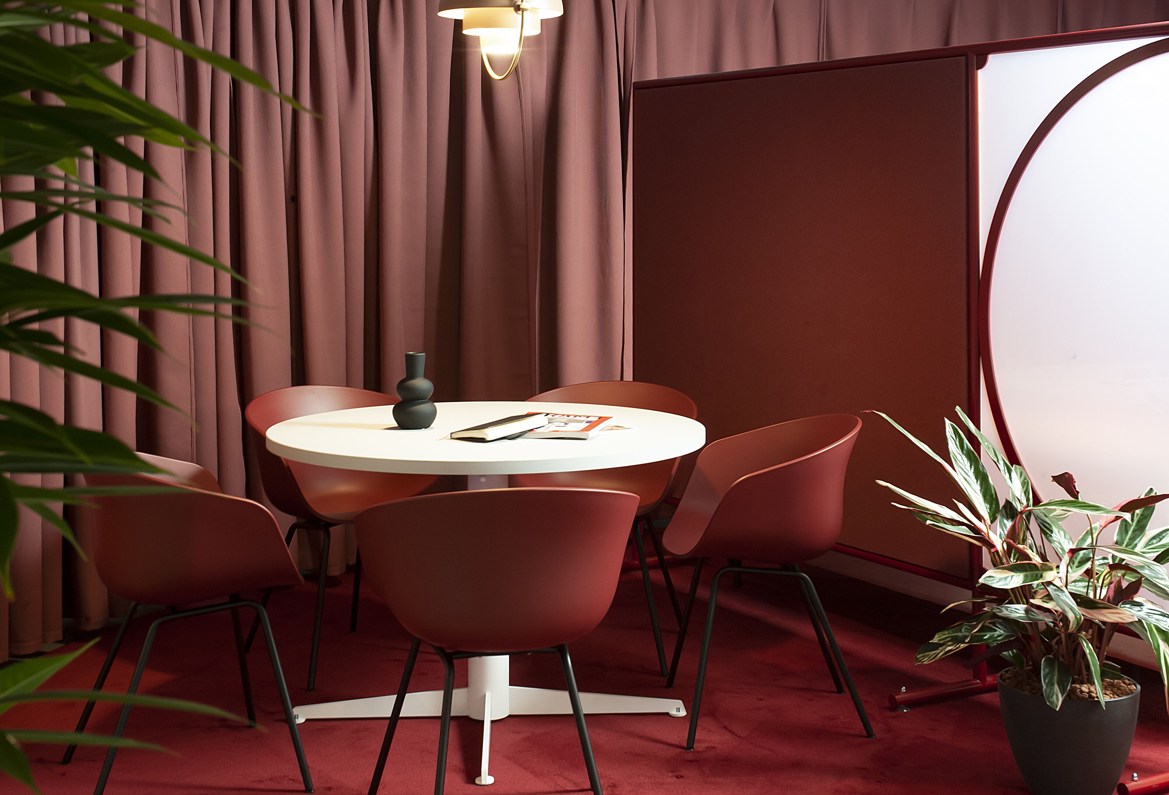 Une table ronde avec six chaises, une plante en pot et une lampe.