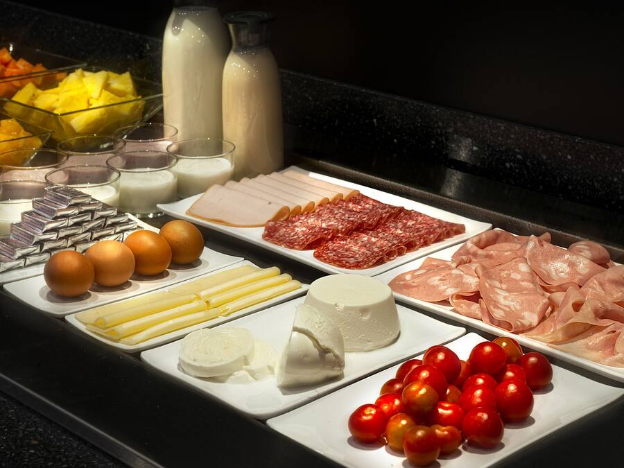 Ein Buffet mit verschiedenen Speisen, darunter Fleisch, Käse, Eier und Obst.