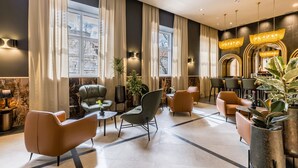 En modern hotellobby med lädersoffor, ett soffbord och en bardisk med växter.