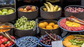 Diversas frutas e legumes dispostos em tigelas e cestas, algumas com pinças para servir.