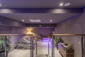 A modern hotel lobby with a reception desk, seating area, and a staircase leading to upper floors.