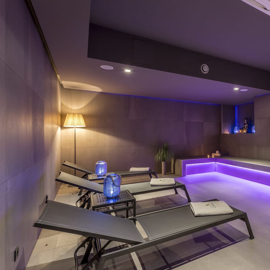 A modern spa area with reclining chairs, a reception desk, and ambient lighting.