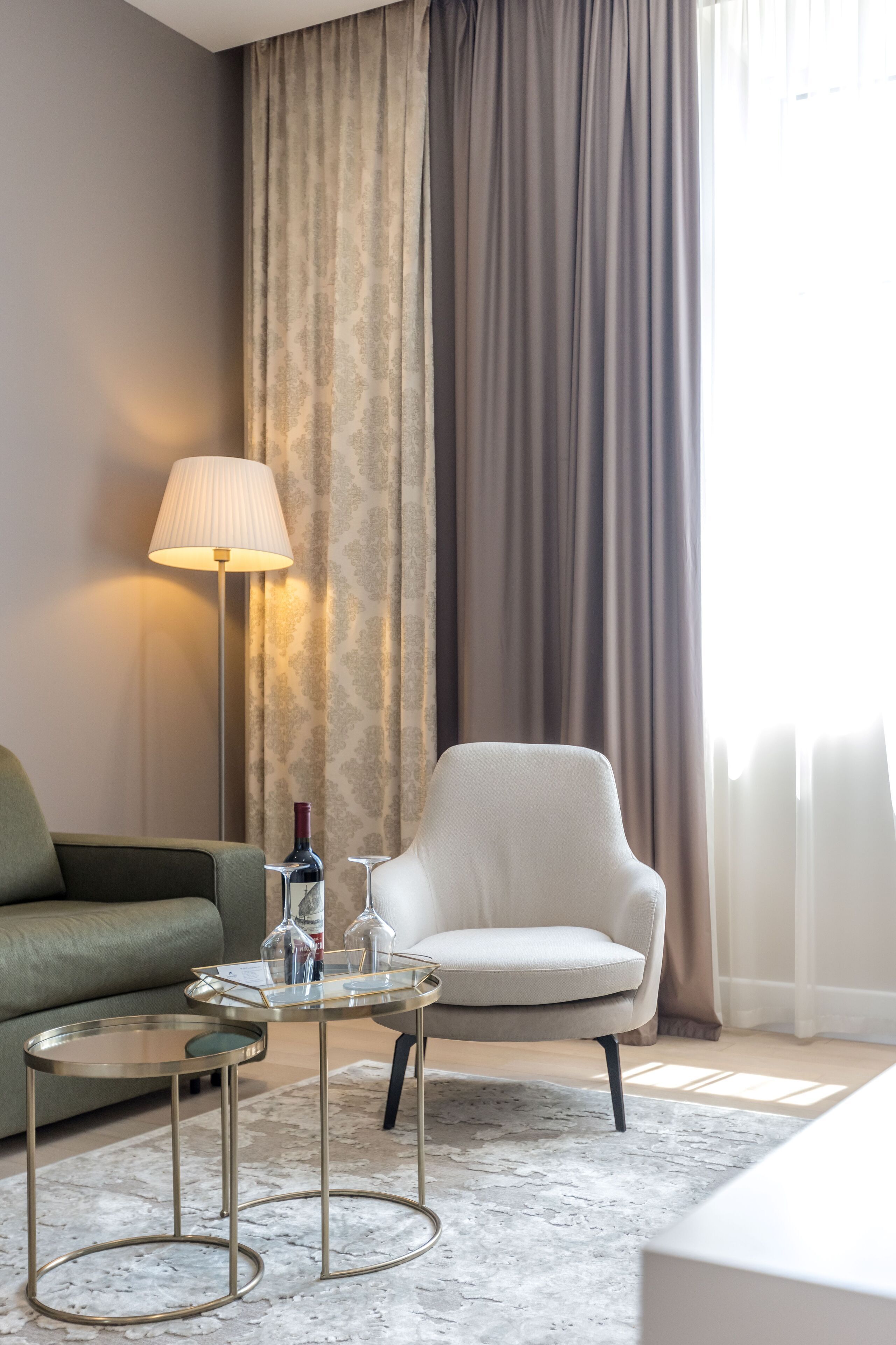 Un salón moderno con un sofá, una silla, una mesita redonda y una lámpara de pie.