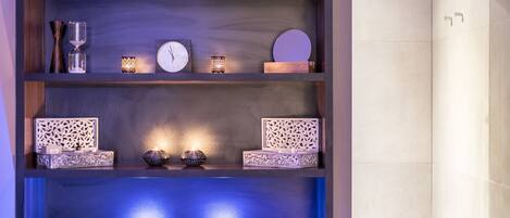Un estante ordenado con varios objetos, como un reloj, velas y cajas decorativas.