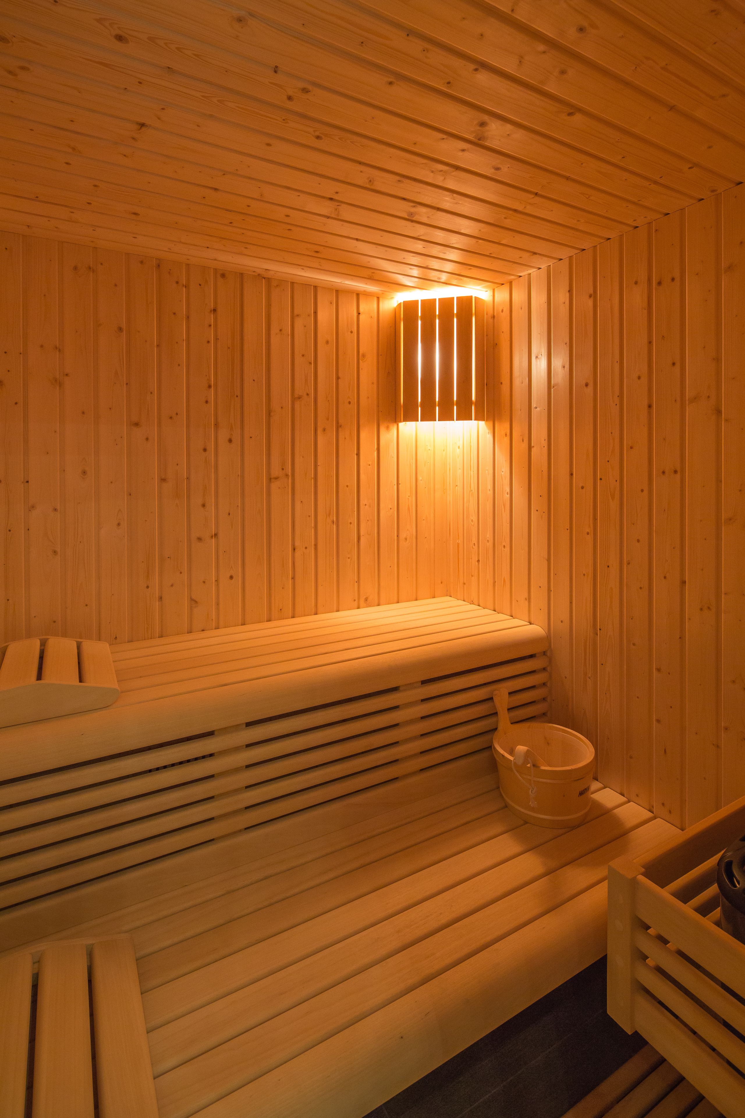A wooden sauna with benches and a bucket.
