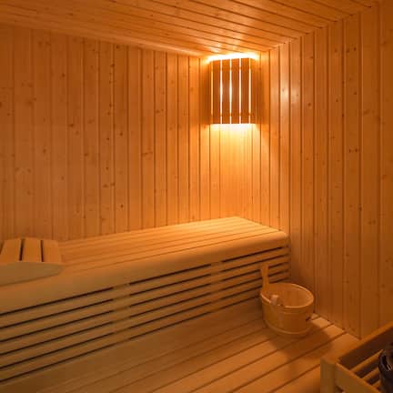 A wooden sauna with benches and a bucket.