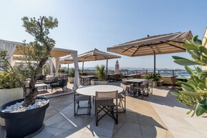 Un patio al aire libre con mesas, sillas, sombrillas y plantas en macetas.