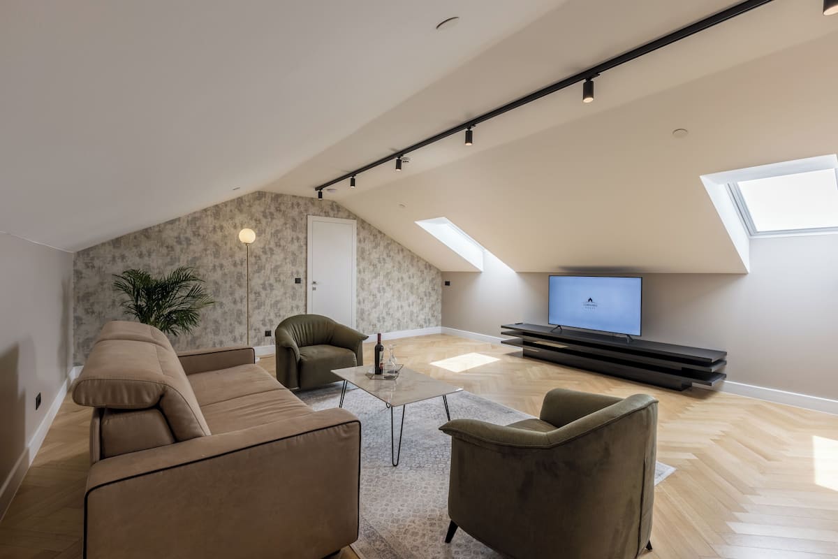 A modern living room with a sofa, armchairs, a coffee table, and a TV.