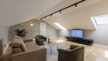 A modern living room with a sofa, armchairs, a coffee table, and a TV.