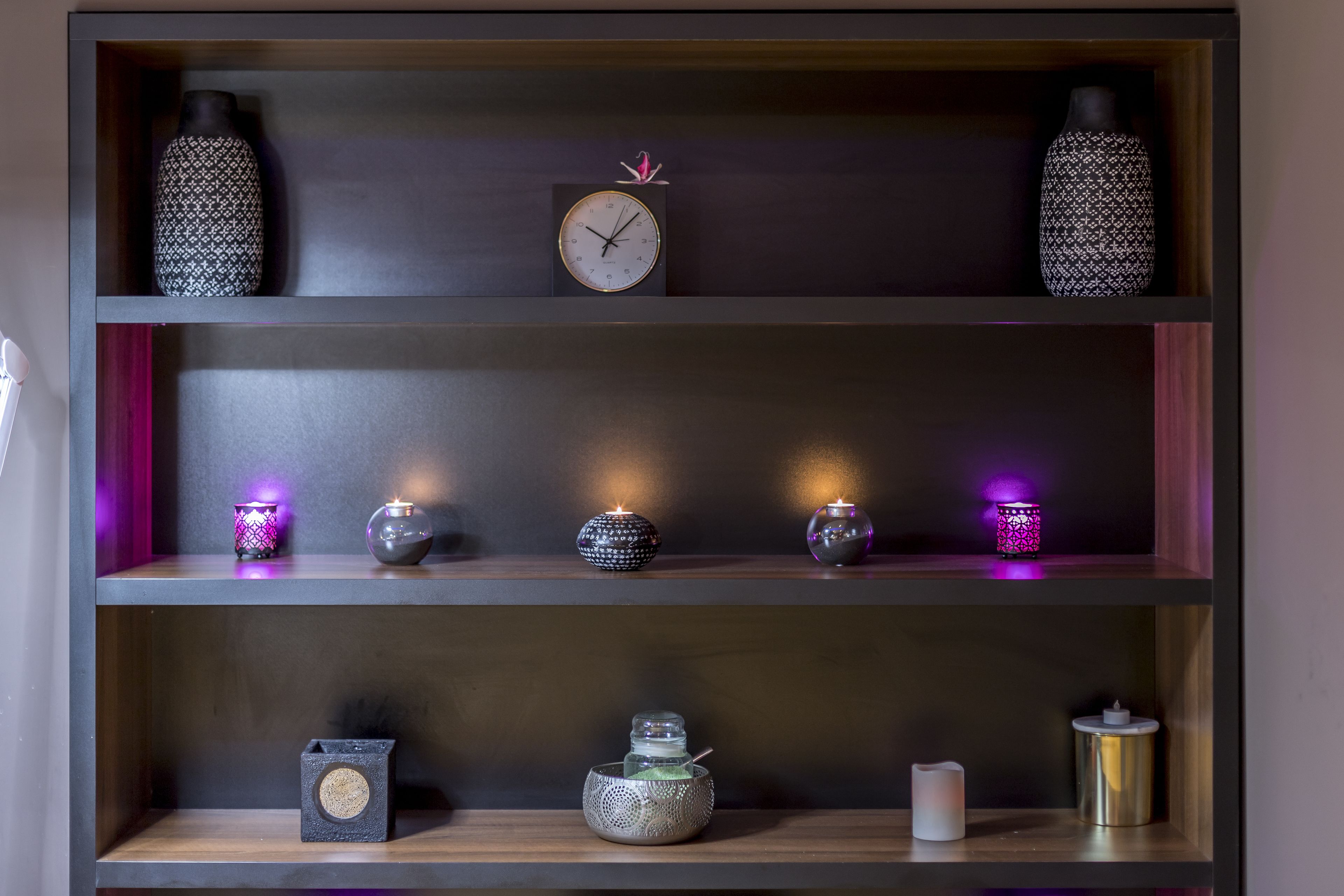 Una repisa con elementos decorativos como jarrones, un reloj y velas.