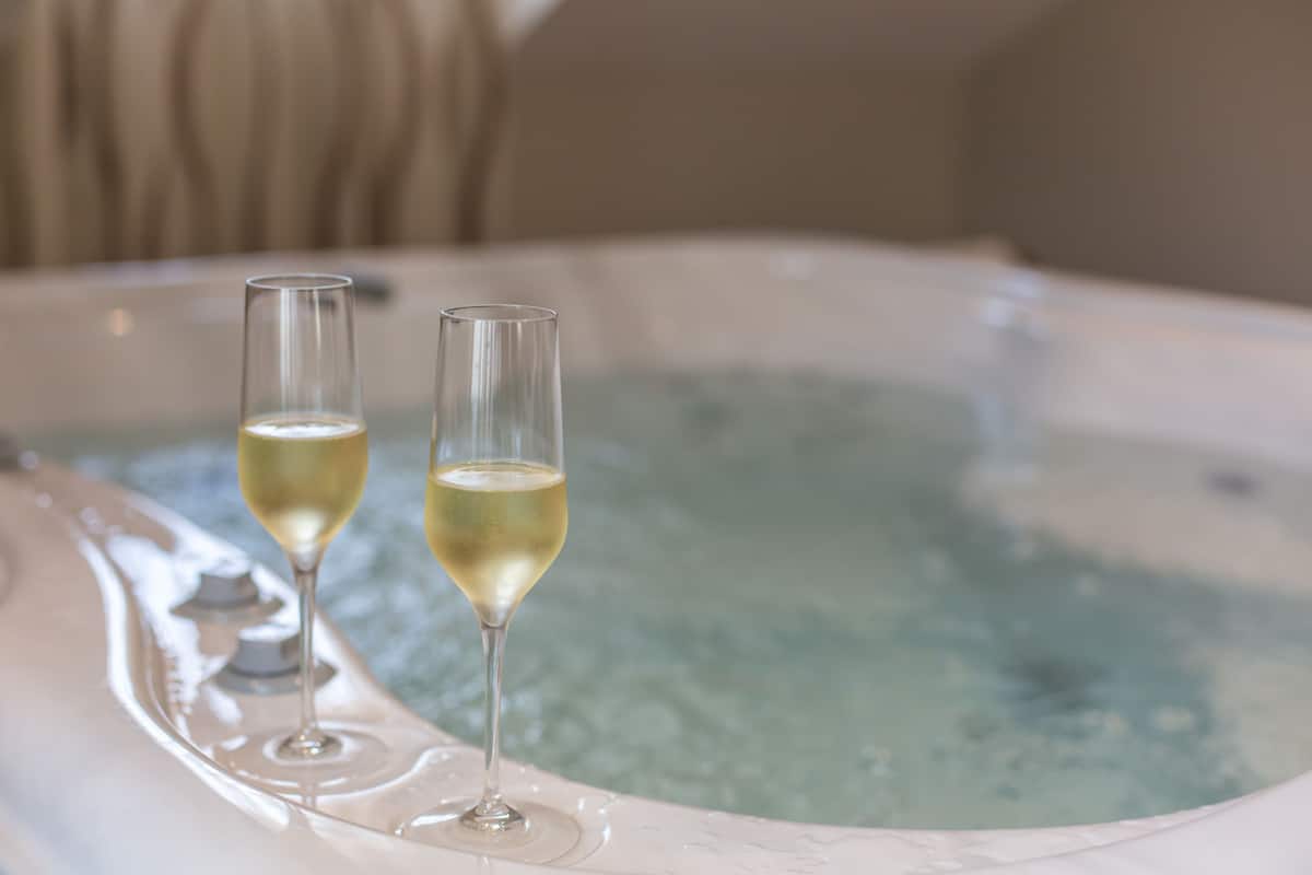 Two glasses of champagne in a hot tub.